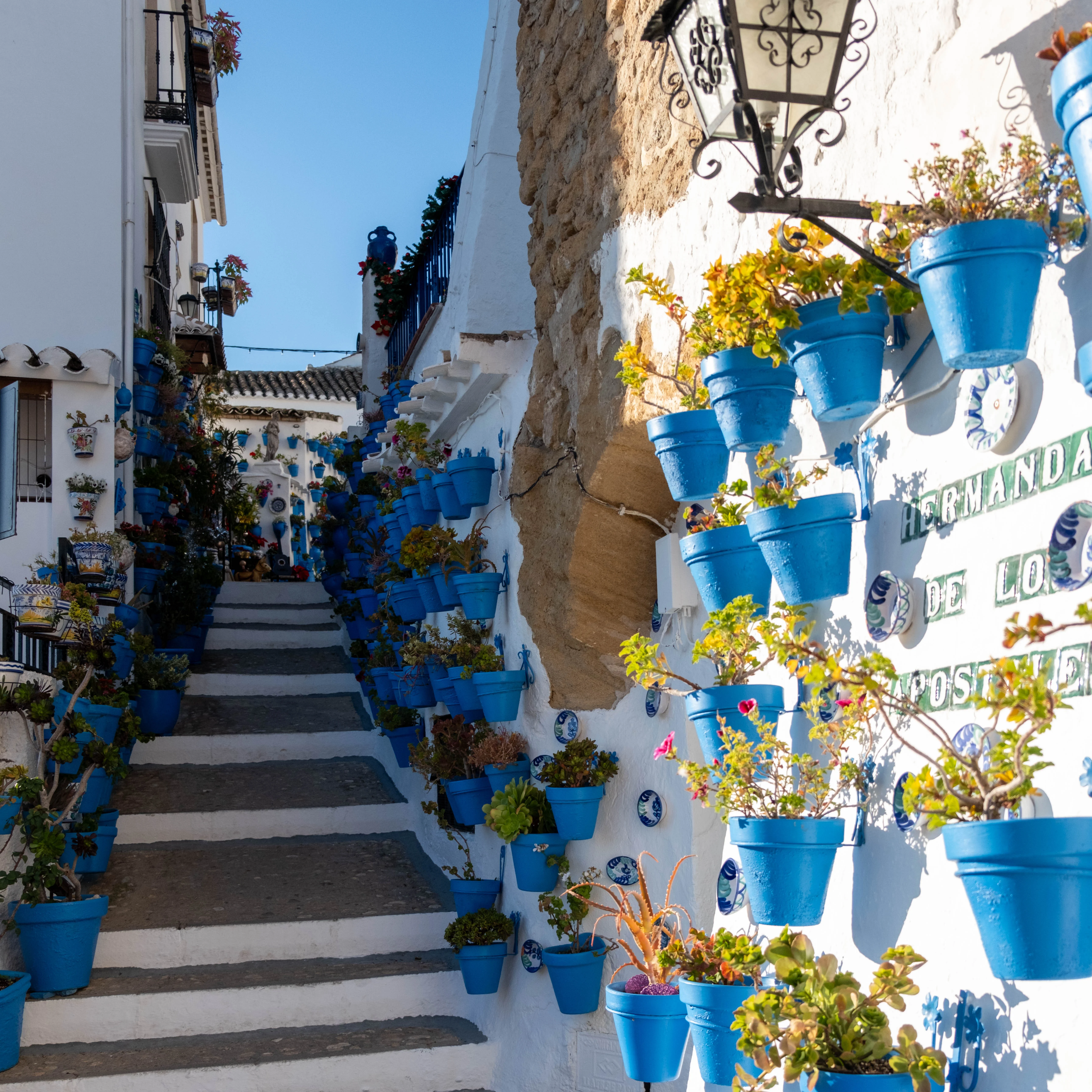 18mm · f/3.2 · 1/2500s · ISO 400
FUJIFILM X-T5 · XF18-55mmF2.8-4 R LM OIS · Dec 30, 2023
Narrow white alleyway with stone steps and blue flower pots.
Iznájar, Spain
© Brandon Cook