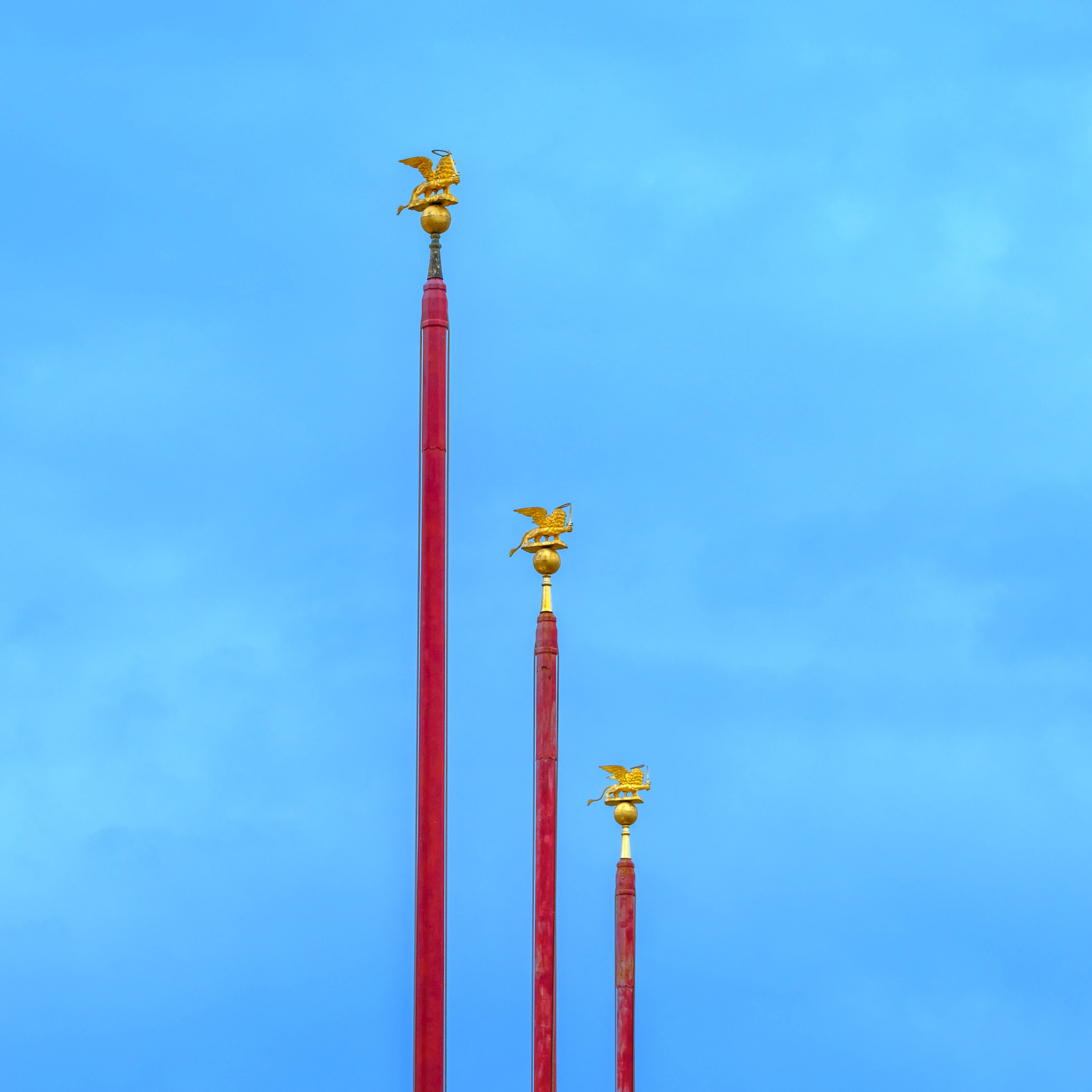 70mm · f/5.6 · 1/850s · ISO 125
FUJIFILM X-T5 · XF70-300mmF4-5.6 R LM OIS WR · Oct 19, 2024
Three red flagpoles topped with golden winged lions.
Venice, Italy
© Brandon Cook