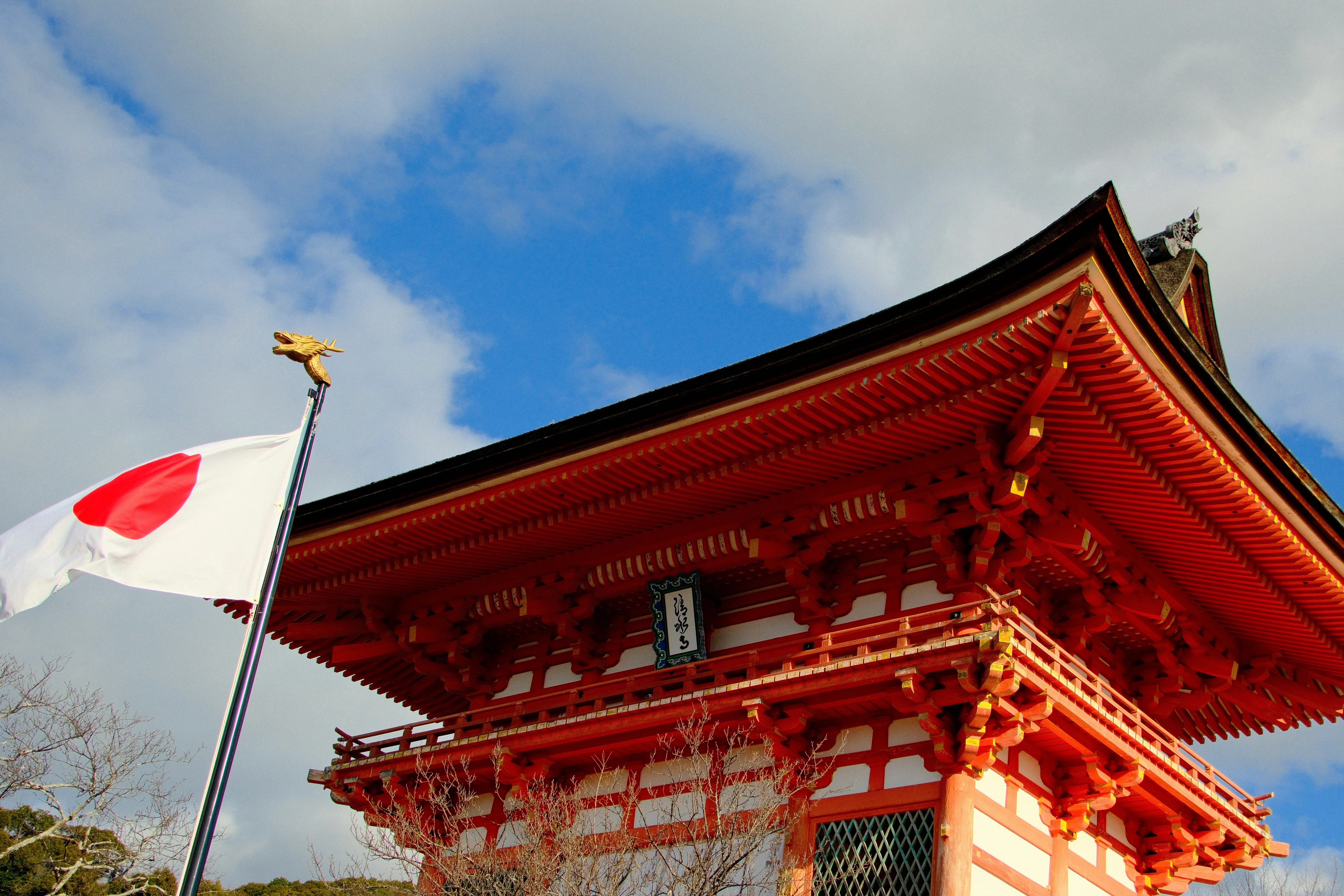 26mm · f/5.6 · 1/1700s · ISO 500
FUJIFILM X-T5 · 16-300mm F3.5-6.7 DC OS | Contemporary 025 · Jan 9, 2026
Japanese flag flying beside a vibrant red temple in Kyoto.
Kyoto, Japan
© Brandon Cook